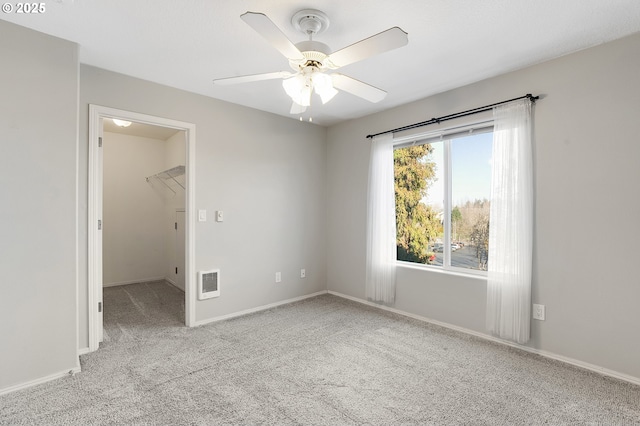 unfurnished bedroom featuring ceiling fan, a closet, a spacious closet, and light carpet