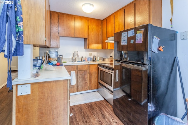 kitchen featuring black refrigerator, dark hardwood / wood-style floors, sink, and stainless steel range with electric cooktop