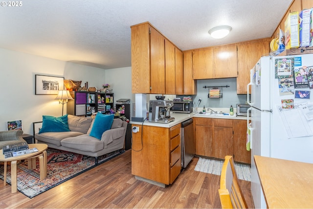 kitchen featuring dark wood-type flooring, stainless steel dishwasher, white fridge, and a textured ceiling