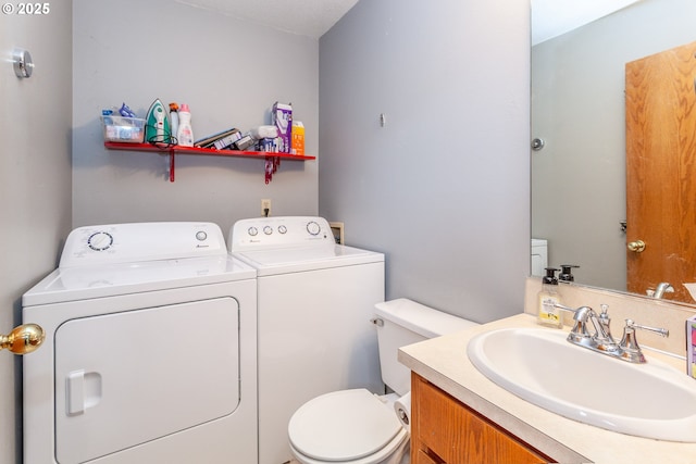 bathroom featuring vanity, washer and dryer, and toilet