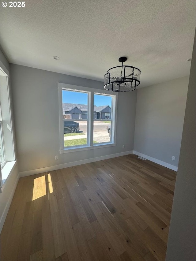 1918 S Holly St, Canby, OR 97013 - unfurnished dining area featuring wood finished floors, a chandelier, baseboards, and a textured ceiling
