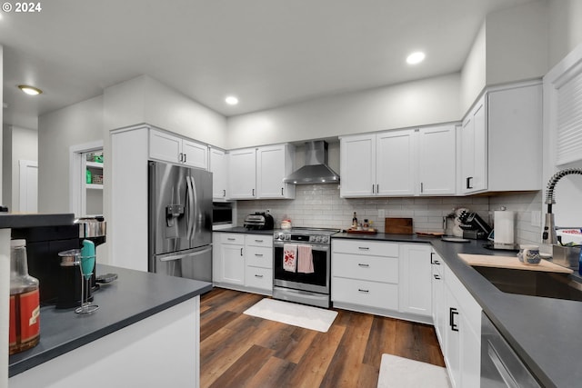 kitchen featuring white cabinets, sink, wall chimney exhaust hood, dark hardwood / wood-style floors, and appliances with stainless steel finishes