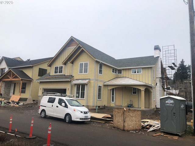 view of front of property featuring a garage, board and batten siding, and a chimney