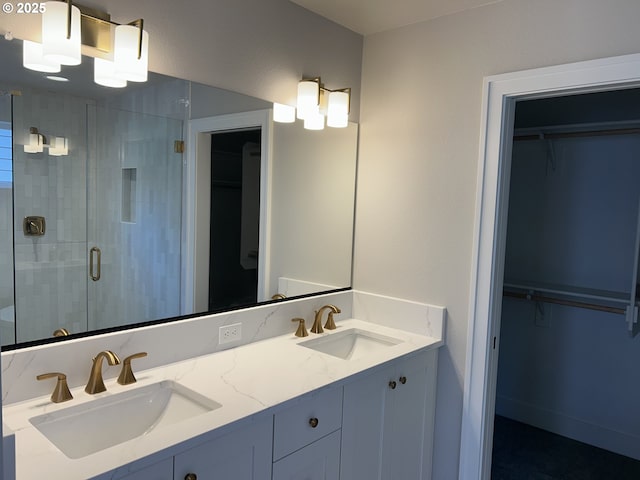 bathroom featuring a shower stall, double vanity, and a walk in closet