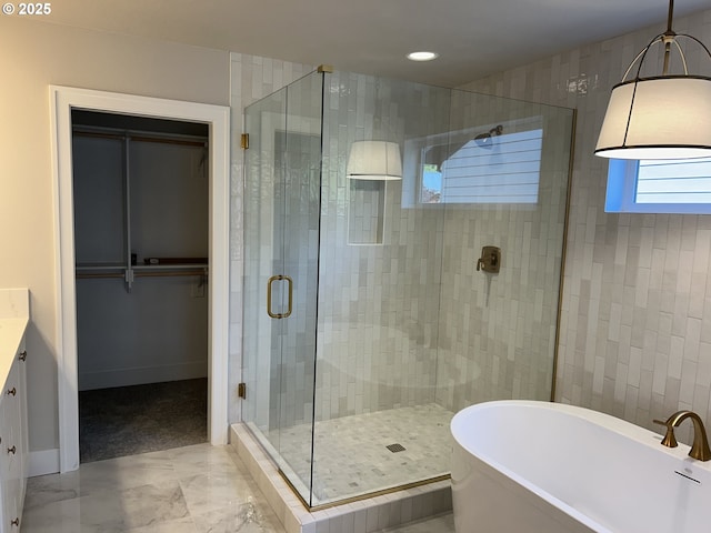 full bathroom with a shower stall, a freestanding bath, marble finish flooring, a spacious closet, and recessed lighting