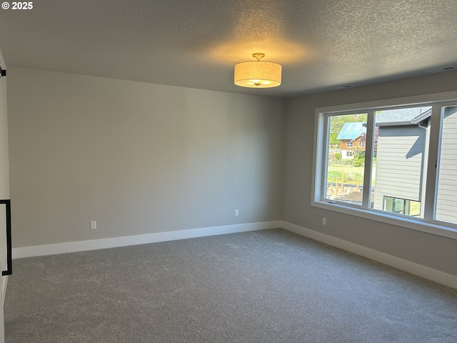 carpeted empty room featuring a textured ceiling and baseboards