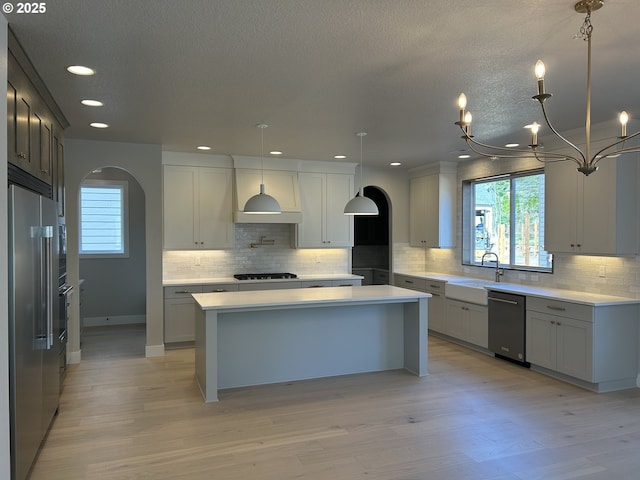 kitchen featuring a sink, high end fridge, dishwasher, gas cooktop, and healthy amount of natural light