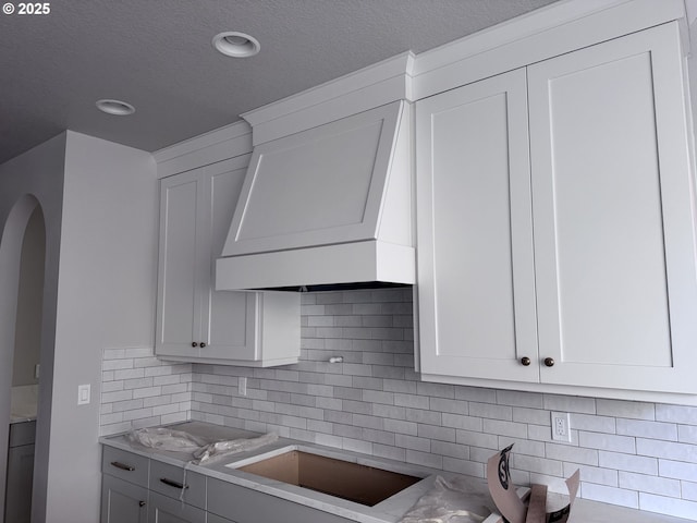 kitchen with white cabinetry, a textured ceiling, backsplash, black electric stovetop, and light countertops