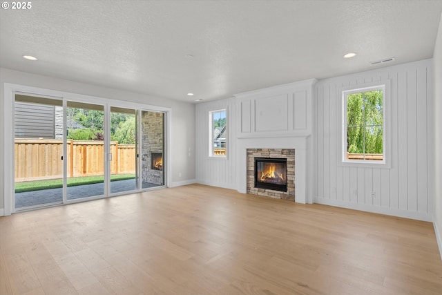 1218 9th St Lot 3, West Linn, OR 97068 - unfurnished living room with a stone fireplace, light wood-style floors, plenty of natural light, a textured ceiling, and recessed lighting