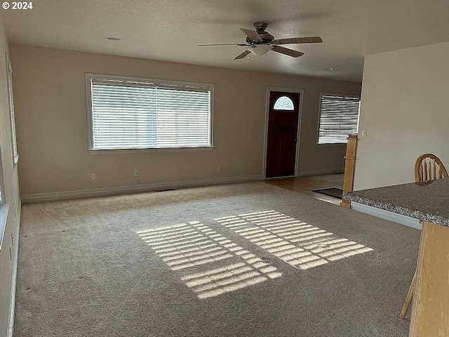 entryway with ceiling fan and light colored carpet