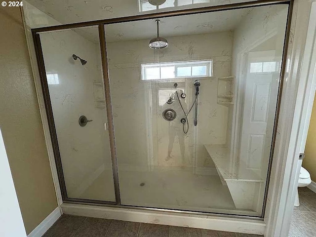 bathroom with toilet, tile patterned flooring, and a shower with shower door