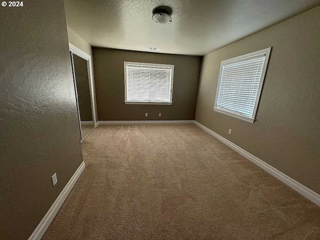 spare room featuring a textured ceiling and carpet flooring