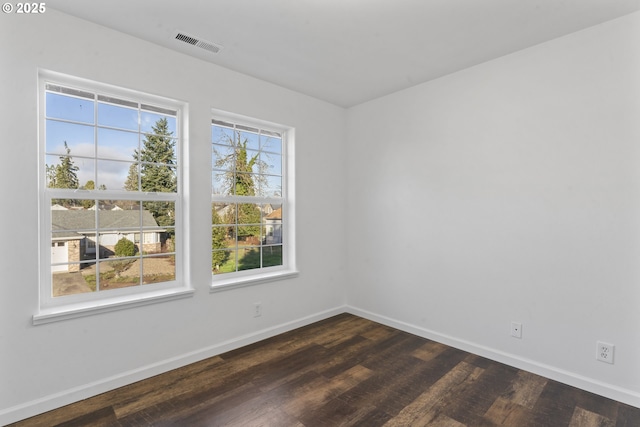 spare room featuring baseboards, visible vents, and dark wood-style flooring