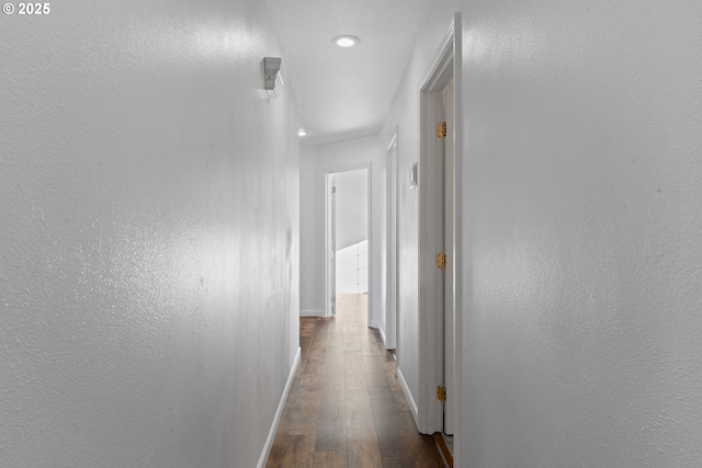 hall featuring baseboards and dark wood-style flooring