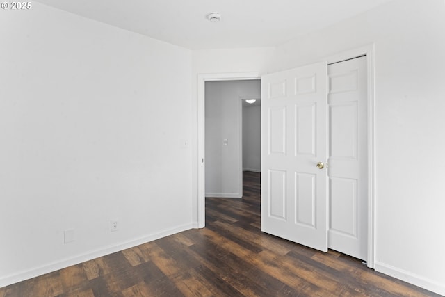 empty room featuring dark wood-style flooring and baseboards