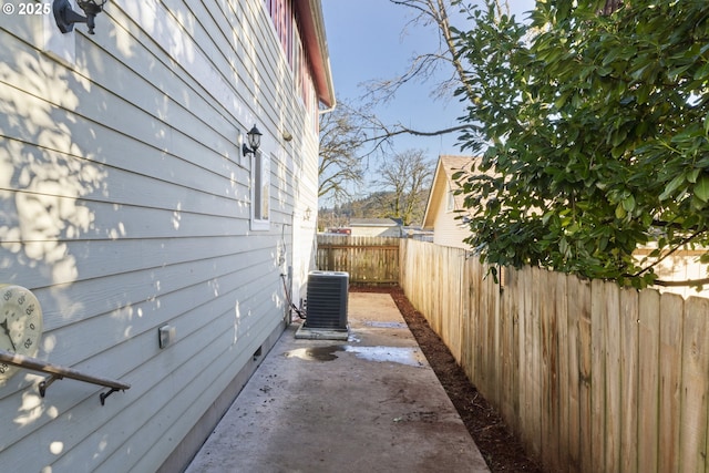 view of side of property featuring central AC and fence