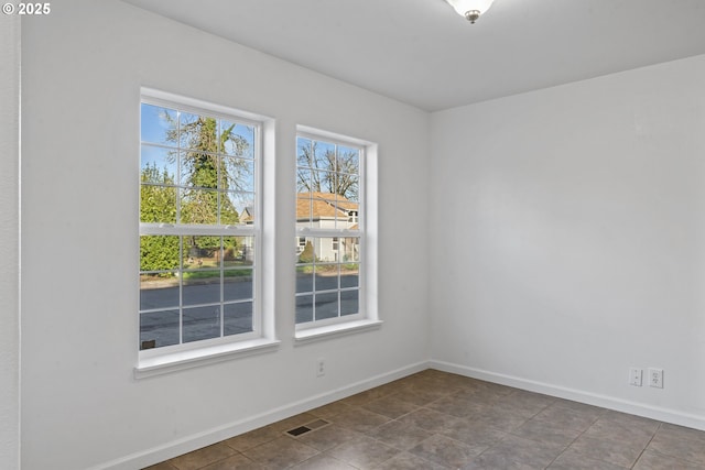 spare room with baseboards and visible vents