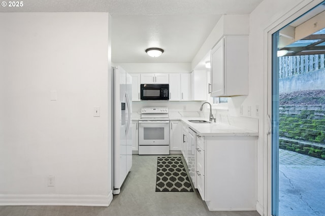 kitchen featuring a textured ceiling, white cabinetry, sink, and white appliances