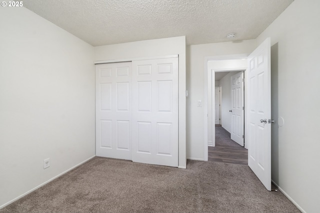 unfurnished bedroom featuring a closet, a textured ceiling, and dark colored carpet