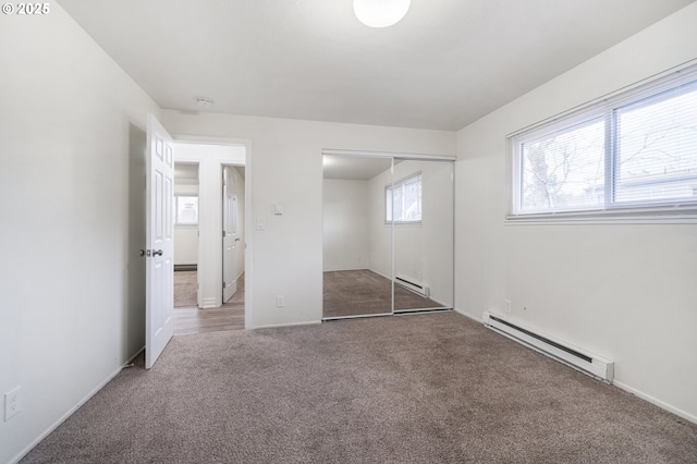 unfurnished bedroom with baseboard heating, a closet, and carpet