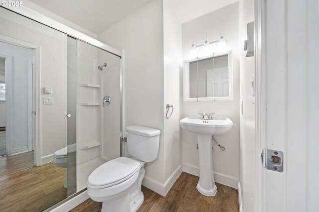 bathroom featuring hardwood / wood-style flooring, toilet, walk in shower, and sink