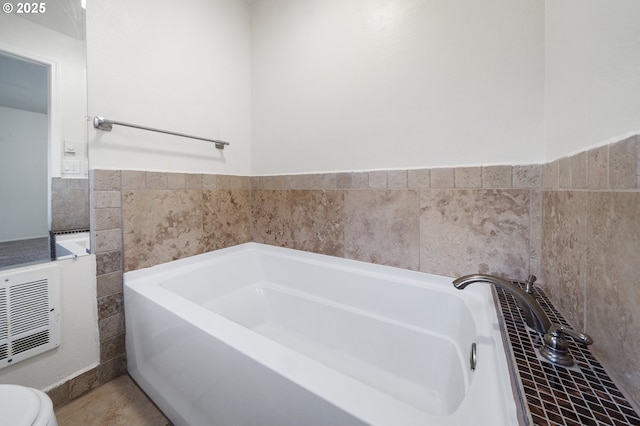 bathroom with heating unit, toilet, and a bathing tub