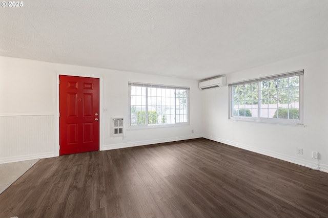 interior space with dark hardwood / wood-style floors, an AC wall unit, and a textured ceiling