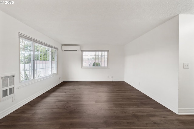 spare room with a wall mounted air conditioner, a textured ceiling, dark hardwood / wood-style floors, and heating unit