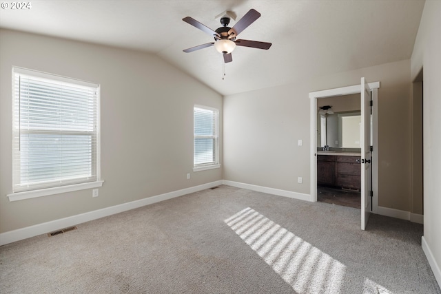 unfurnished bedroom with ceiling fan, light colored carpet, connected bathroom, and vaulted ceiling