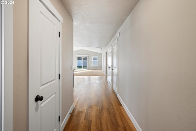 hall with wood-type flooring and lofted ceiling