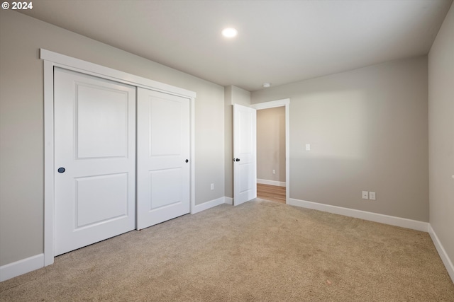 unfurnished bedroom with a closet and light colored carpet