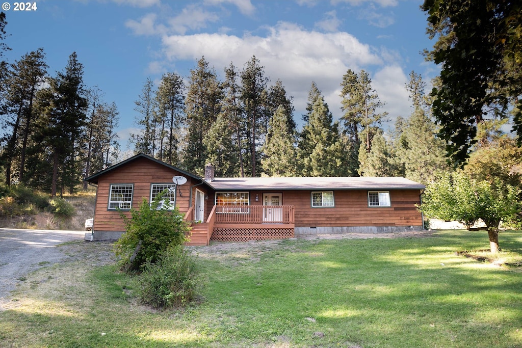 view of front facade featuring a front yard, crawl space, a wooden deck, and gravel driveway