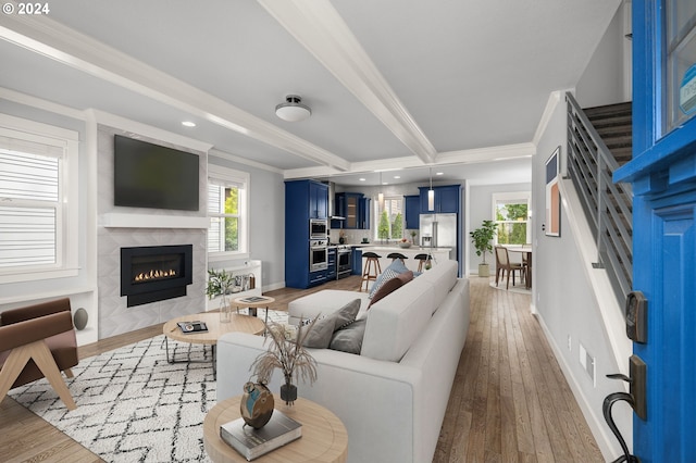 living room with crown molding, plenty of natural light, a tile fireplace, and light hardwood / wood-style floors