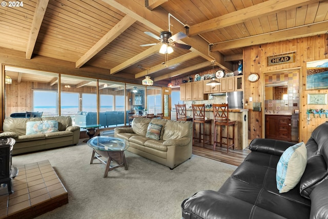 living room with ceiling fan, wooden walls, and beam ceiling