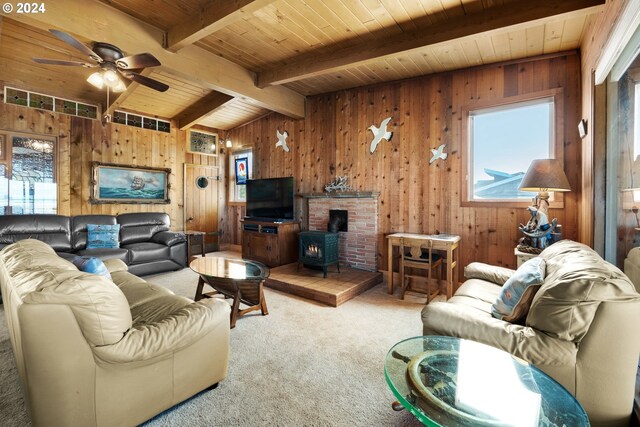 living room with a wood stove, carpet floors, and wood walls