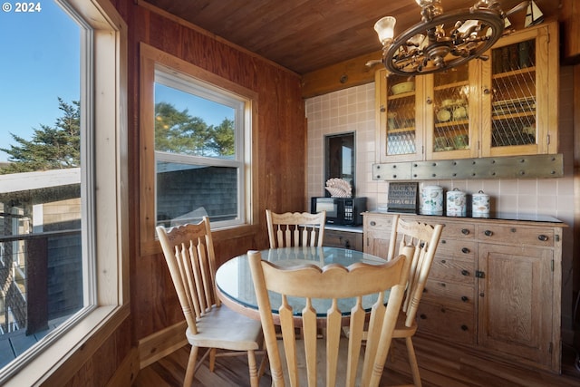 dining area featuring wood walls, wooden ceiling, dark hardwood / wood-style floors, and an inviting chandelier