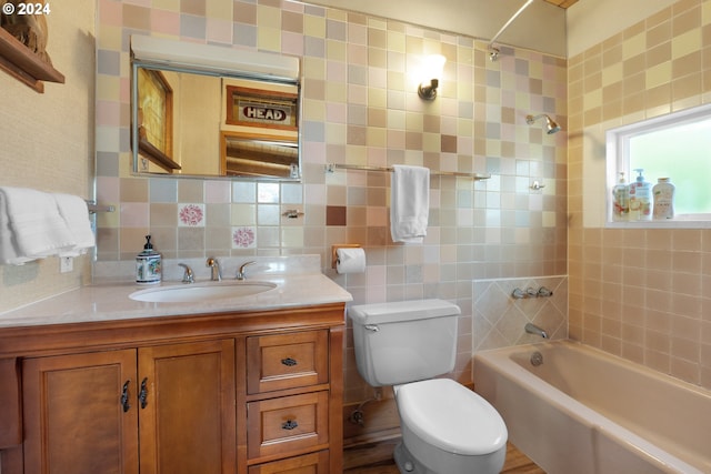 full bathroom featuring tile walls, vanity, tiled shower / bath combo, and toilet