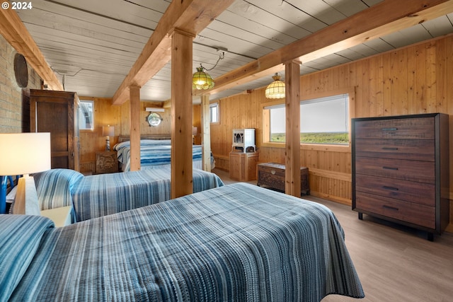 bedroom featuring wood walls, beam ceiling, and light hardwood / wood-style flooring