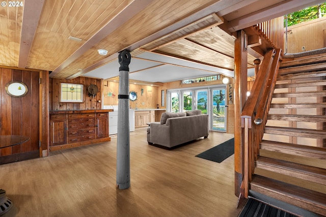 unfurnished living room featuring wood walls, light hardwood / wood-style floors, beamed ceiling, and wood ceiling