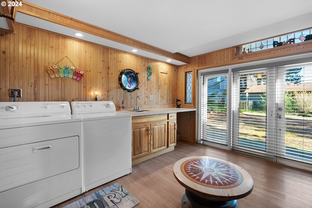 laundry area featuring cabinets, sink, washer and dryer, wooden walls, and light wood-type flooring