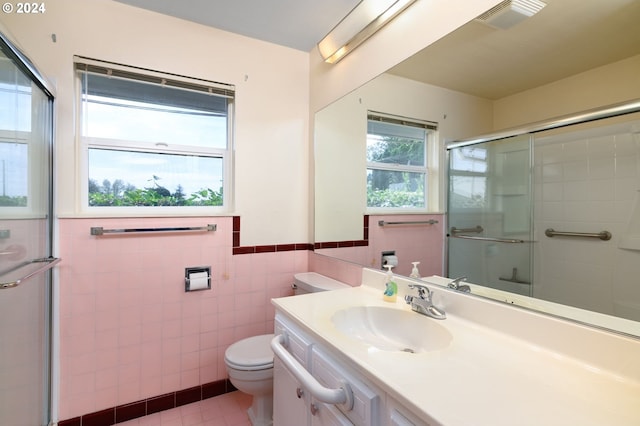 bathroom with toilet, tile patterned flooring, vanity, tile walls, and walk in shower