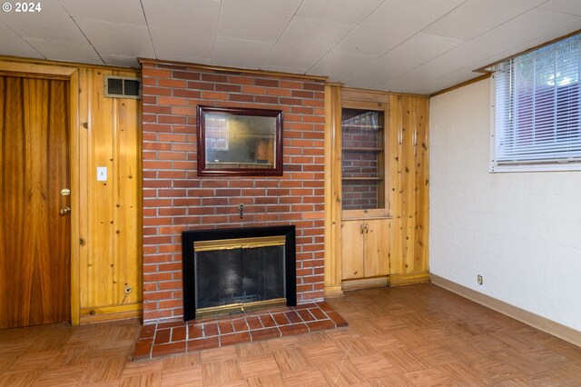 unfurnished living room featuring parquet flooring, a fireplace, and wood walls