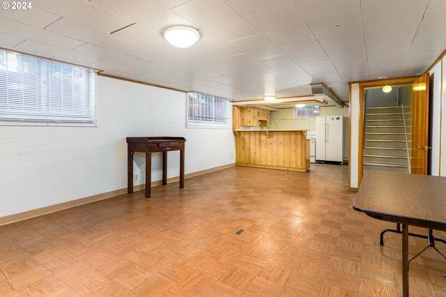 basement with white fridge and light parquet floors