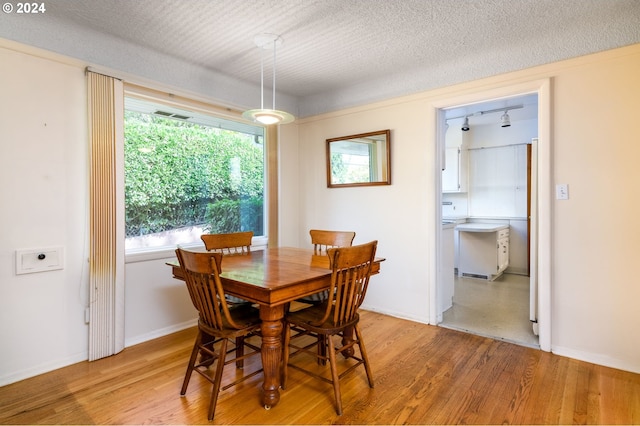 dining area with light hardwood / wood-style flooring and a textured ceiling