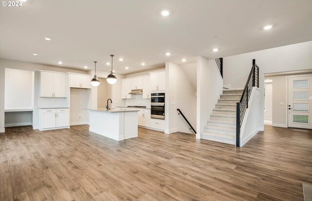 17477 NW Antonio St, Portland, OR 97229 - kitchen featuring open floor plan, stainless steel double oven, a sink, and light wood-type flooring