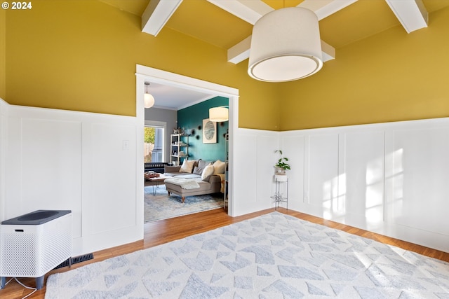 interior space with crown molding, light hardwood / wood-style floors, and beam ceiling