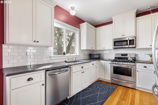 kitchen with white cabinets, sink, light wood-type flooring, and appliances with stainless steel finishes