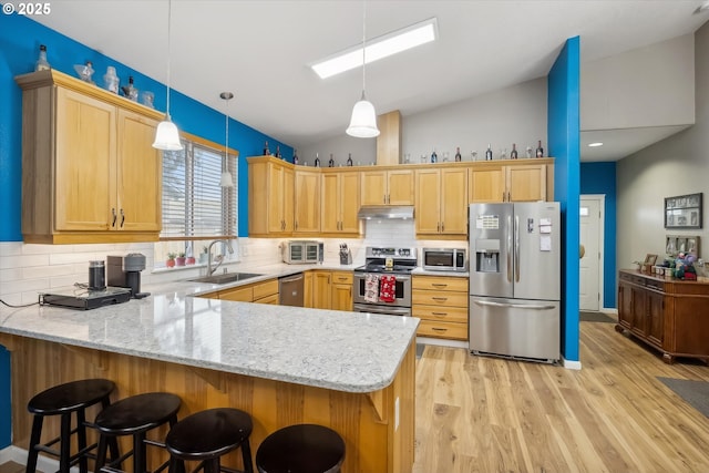 kitchen featuring kitchen peninsula, decorative light fixtures, stainless steel appliances, and lofted ceiling