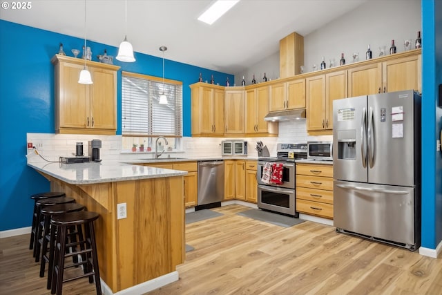 kitchen featuring pendant lighting, light hardwood / wood-style floors, light stone counters, kitchen peninsula, and stainless steel appliances