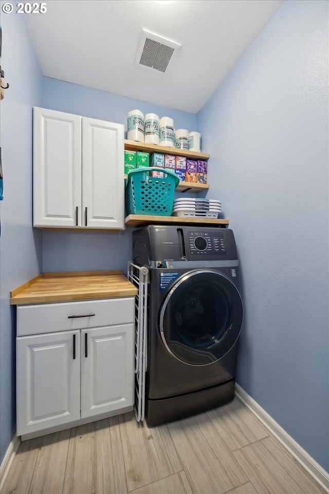 clothes washing area featuring cabinets, washer / clothes dryer, and light hardwood / wood-style flooring